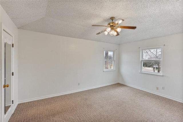 carpeted spare room with a textured ceiling, a ceiling fan, and baseboards