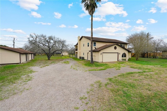 view of side of property featuring a yard, a chimney, central AC, a garage, and driveway