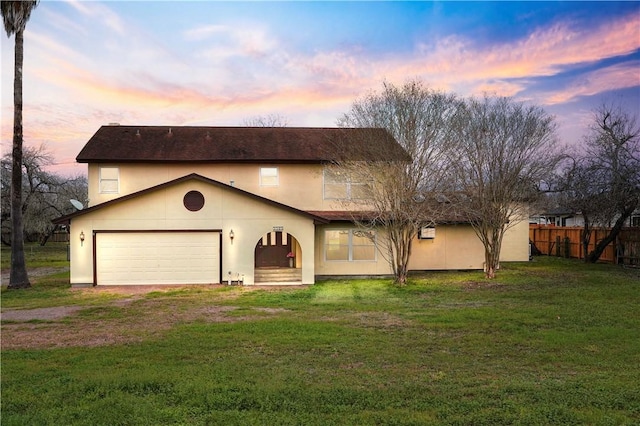 view of front of property featuring stucco siding, a front yard, fence, a garage, and driveway