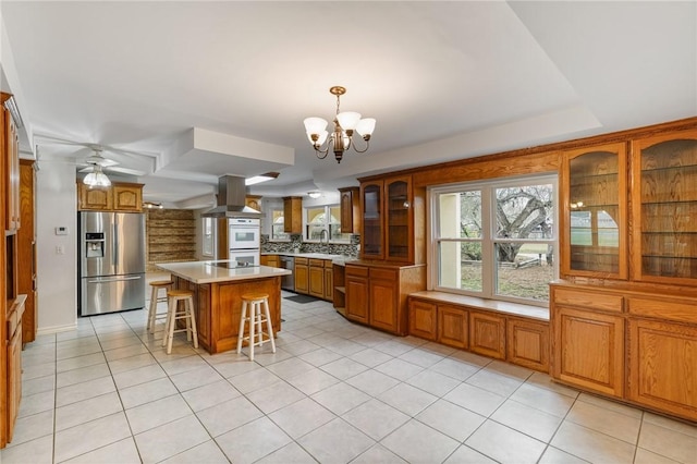 kitchen with light countertops, appliances with stainless steel finishes, glass insert cabinets, a kitchen island, and a kitchen breakfast bar