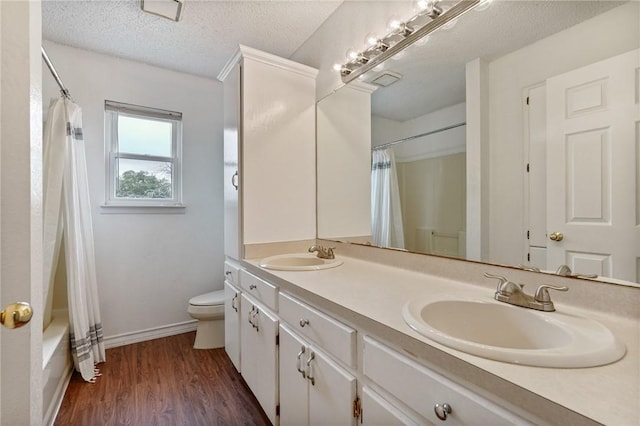 bathroom with a sink, a textured ceiling, toilet, and wood finished floors