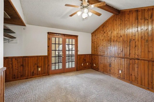 empty room featuring a wainscoted wall, wooden walls, and french doors