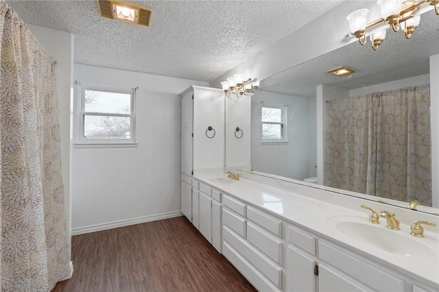 bathroom with wood finished floors, a sink, baseboards, and an inviting chandelier