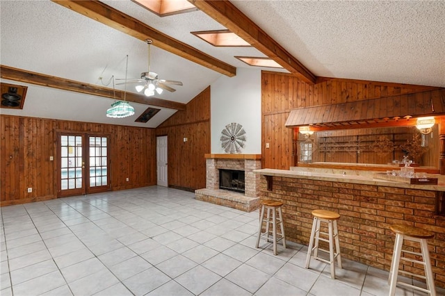 unfurnished living room with french doors, light tile patterned flooring, wood walls, and a textured ceiling