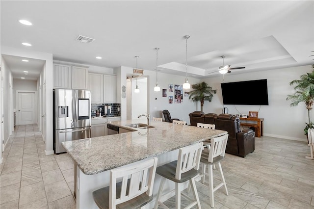 kitchen with white cabinets, a breakfast bar area, ceiling fan, tasteful backsplash, and stainless steel appliances