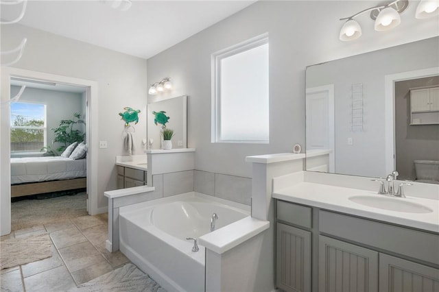 bathroom featuring tile patterned flooring, a bath, vanity, and toilet