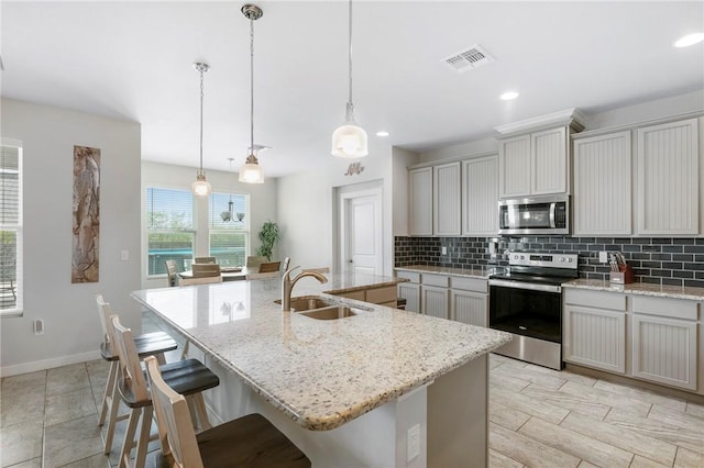 kitchen featuring a center island with sink, decorative light fixtures, sink, and stainless steel appliances