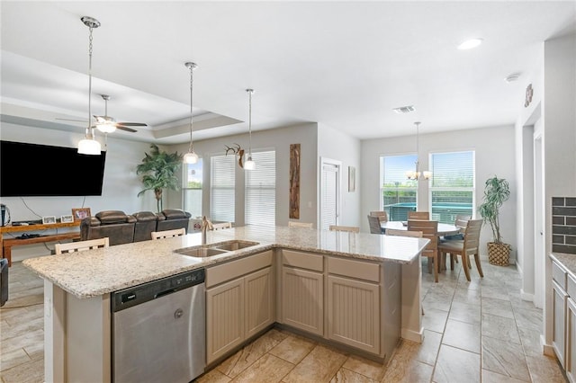 kitchen featuring sink, stainless steel dishwasher, a tray ceiling, a center island with sink, and ceiling fan with notable chandelier