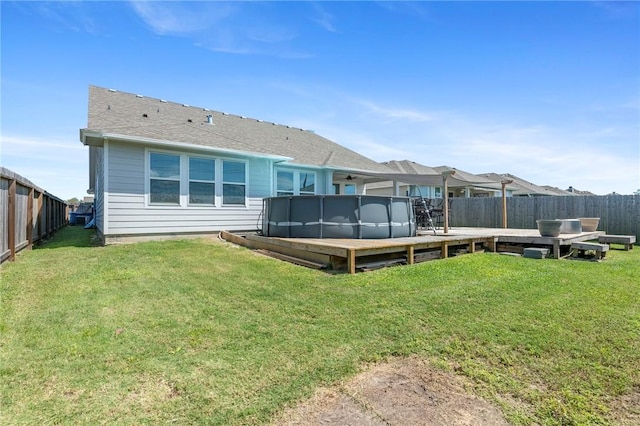 rear view of house with a swimming pool side deck and a yard