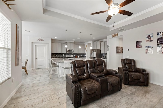 living room featuring ceiling fan, ornamental molding, and a tray ceiling