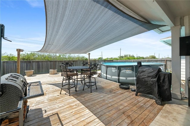 deck with area for grilling and a fenced in pool