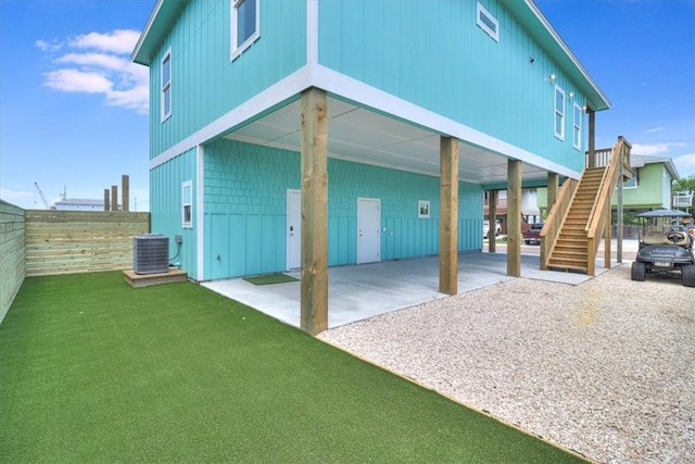 235 Port Mansfield St, Port Aransas, TX 78373 - rear view of property featuring central AC unit, a carport, stairs, and gravel driveway