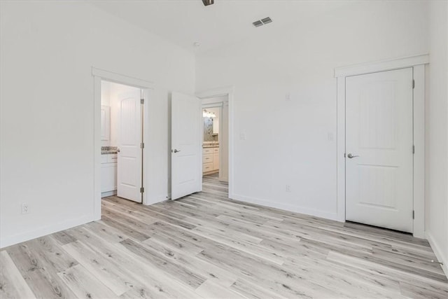 235 Port Mansfield St, Port Aransas, TX 78373 - unfurnished bedroom with light wood finished floors, ensuite bath, and baseboards