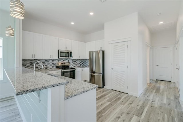 235 Port Mansfield St, Port Aransas, TX 78373 - kitchen featuring stainless steel appliances, a peninsula, light wood-type flooring, light stone counters, and recessed lighting