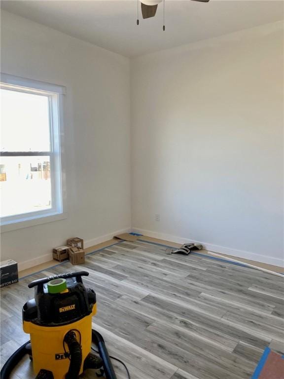 empty room featuring baseboards, wood finished floors, and ceiling fan