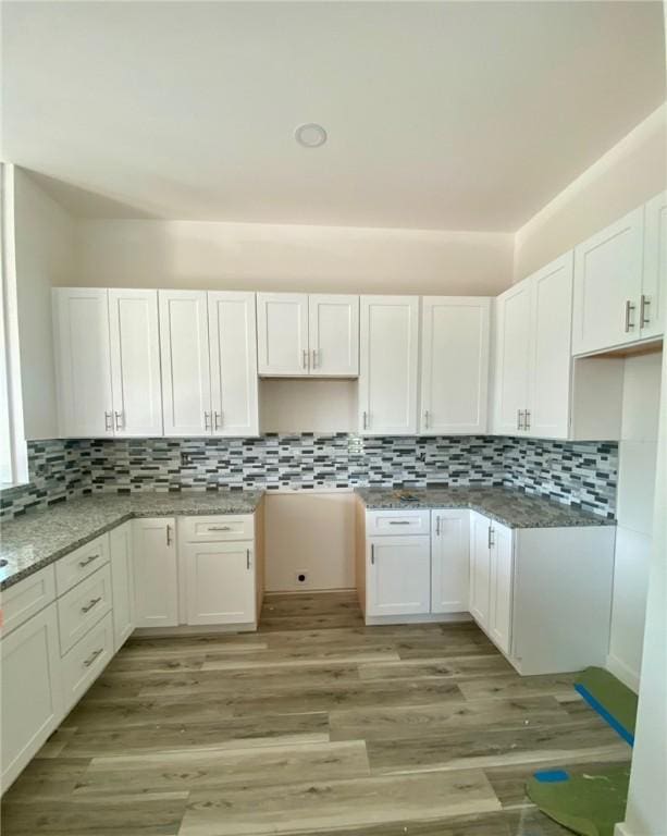 kitchen with white cabinets, light wood finished floors, and decorative backsplash