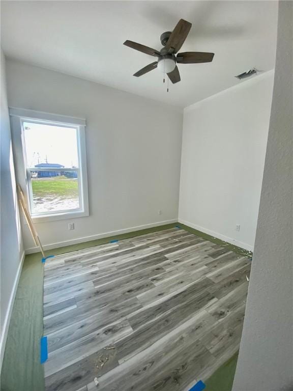 unfurnished room featuring visible vents, baseboards, a ceiling fan, and wood finished floors