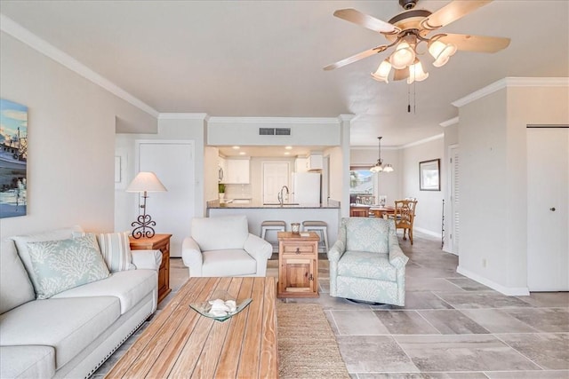 living area featuring visible vents, crown molding, baseboards, and ceiling fan with notable chandelier