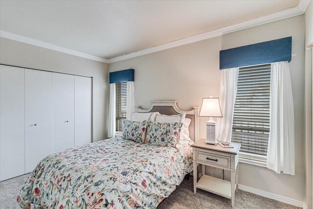 carpeted bedroom with baseboards, ornamental molding, and a closet