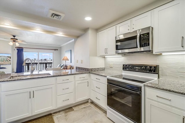 kitchen with visible vents, white cabinets, electric stove, stainless steel microwave, and a sink