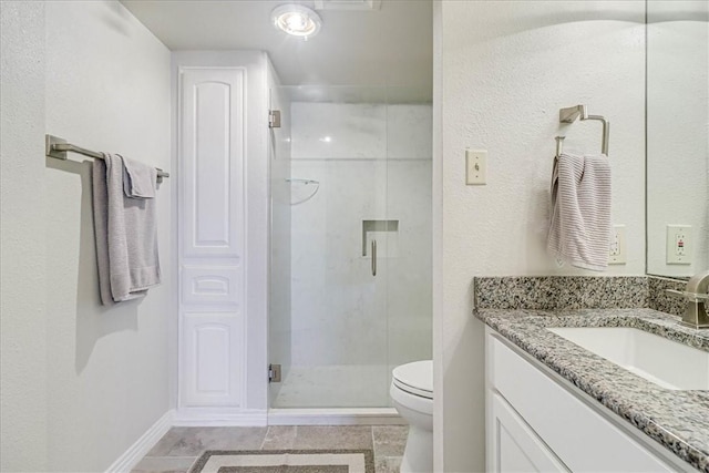 bathroom featuring a shower stall, baseboards, vanity, and toilet