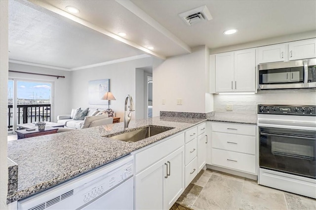 kitchen featuring white appliances, visible vents, light stone countertops, white cabinetry, and a sink