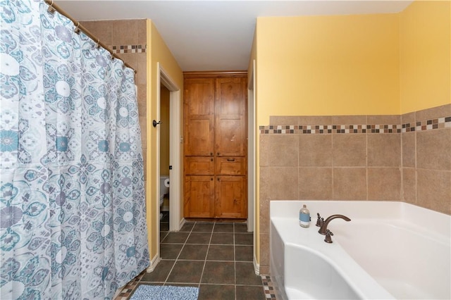 bathroom featuring tile patterned flooring, a bathtub, toilet, and tile walls