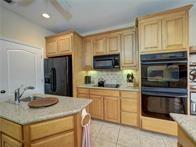 15230 Isabella Ct, Corpus Christi, TX 78418 - kitchen featuring black appliances, tasteful backsplash, light brown cabinetry, light tile patterned floors, and recessed lighting