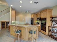 15230 Isabella Ct, Corpus Christi, TX 78418 - kitchen with recessed lighting, a peninsula, a breakfast bar area, fridge, and light brown cabinetry