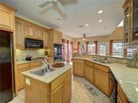 15230 Isabella Ct, Corpus Christi, TX 78418 - kitchen with a ceiling fan, black appliances, a sink, an island with sink, and light countertops