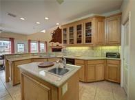 15230 Isabella Ct, Corpus Christi, TX 78418 - kitchen featuring a peninsula, a kitchen island with sink, light tile patterned floors, a sink, and decorative backsplash