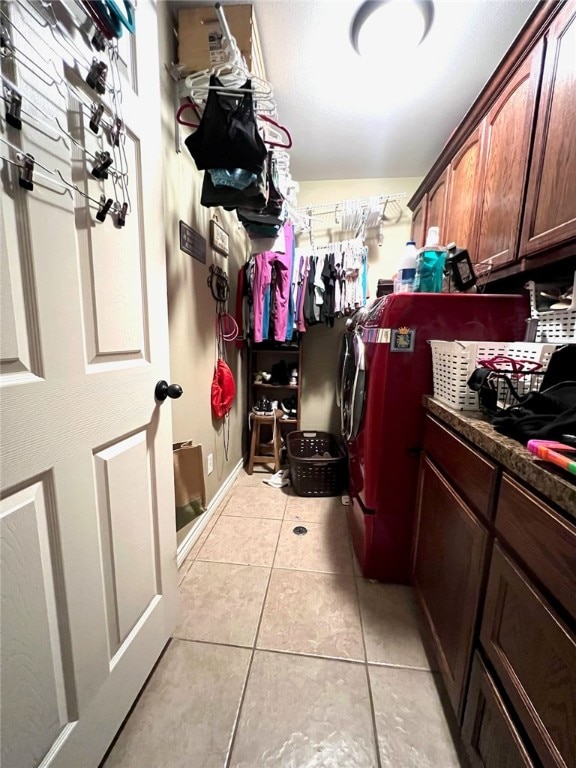 washroom featuring cabinets, light tile patterned floors, and washer and clothes dryer