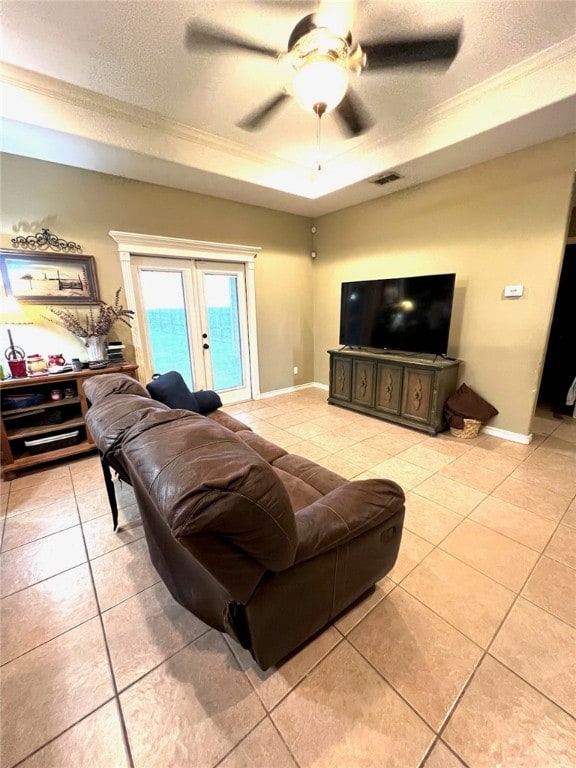 tiled living room with french doors, a textured ceiling, ceiling fan, crown molding, and a tray ceiling