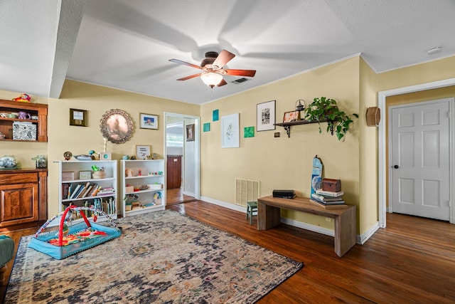 recreation room featuring a textured ceiling, dark hardwood / wood-style floors, and ceiling fan