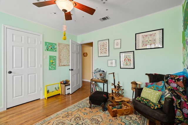 sitting room with hardwood / wood-style floors and ceiling fan