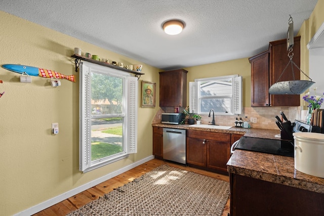 kitchen with light hardwood / wood-style floors, sink, appliances with stainless steel finishes, tasteful backsplash, and a textured ceiling