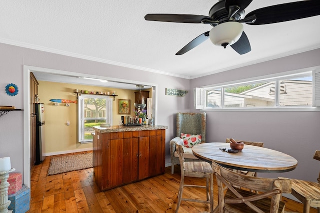 dining space with wood-type flooring, ceiling fan, and crown molding