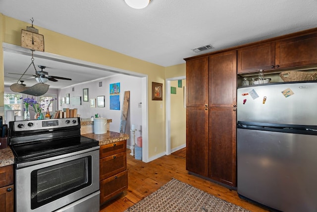 kitchen featuring stainless steel appliances, a textured ceiling, dark brown cabinets, dark wood-type flooring, and ceiling fan