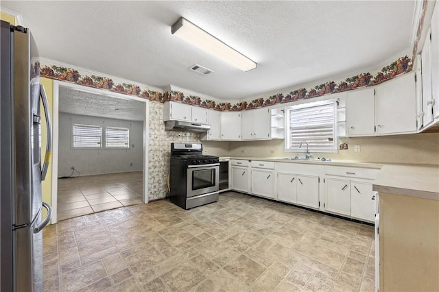 342 Davis Rd, Taft, TX 78390 - kitchen featuring appliances with stainless steel finishes, under cabinet range hood, light countertops, a textured ceiling, and stone finish flooring