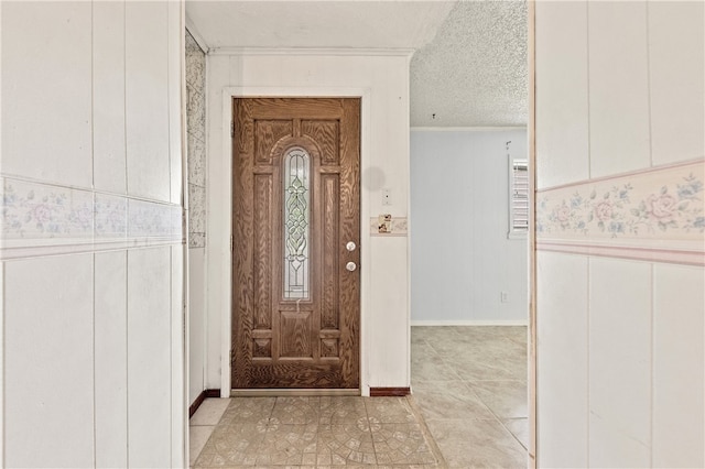 tiled foyer with a textured ceiling and crown molding