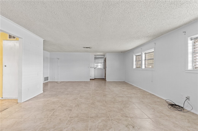 spare room with light tile patterned flooring, a textured ceiling, and ornamental molding