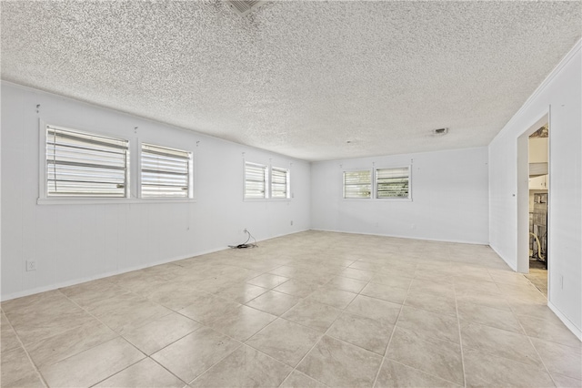 empty room featuring light tile patterned flooring, a textured ceiling, and ornamental molding