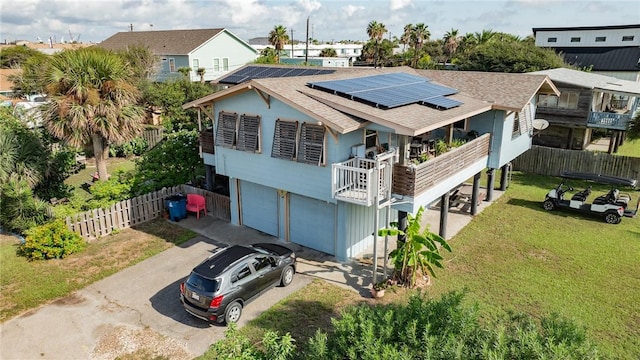 424 Trojan St, Port Aransas, TX 78373 - back of house featuring driveway, solar panels, an attached garage, a balcony, and a shingled roof