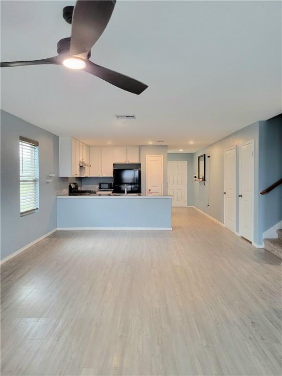 kitchen featuring kitchen peninsula, white cabinetry, refrigerator, and light hardwood / wood-style floors