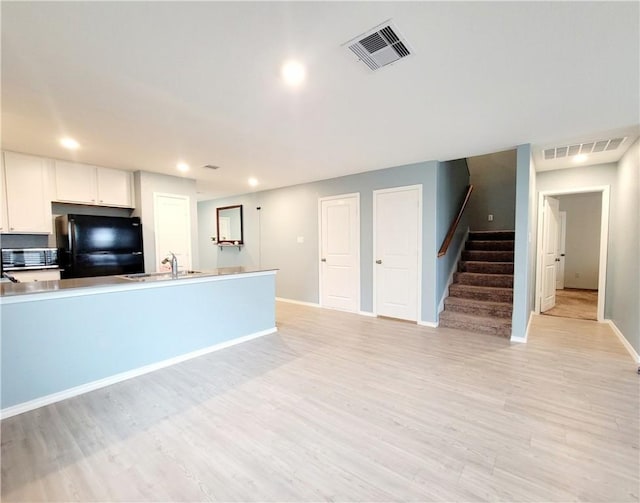 kitchen featuring sink, white cabinets, light hardwood / wood-style floors, and fridge