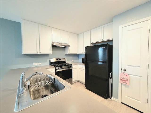 kitchen featuring stainless steel range with gas cooktop, black fridge, sink, and white cabinets