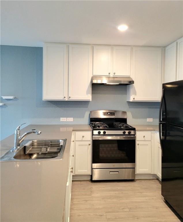 kitchen featuring black refrigerator, white cabinetry, and stainless steel range with gas stovetop