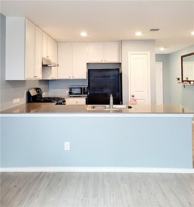 kitchen featuring kitchen peninsula, stainless steel appliances, white cabinetry, and sink