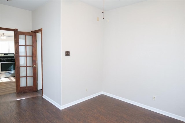 empty room featuring dark wood-type flooring, baseboards, and a ceiling fan