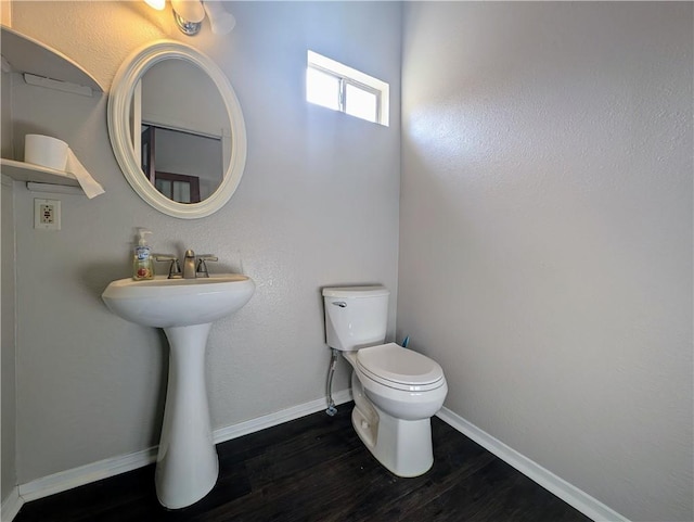 half bathroom featuring wood finished floors, toilet, and baseboards